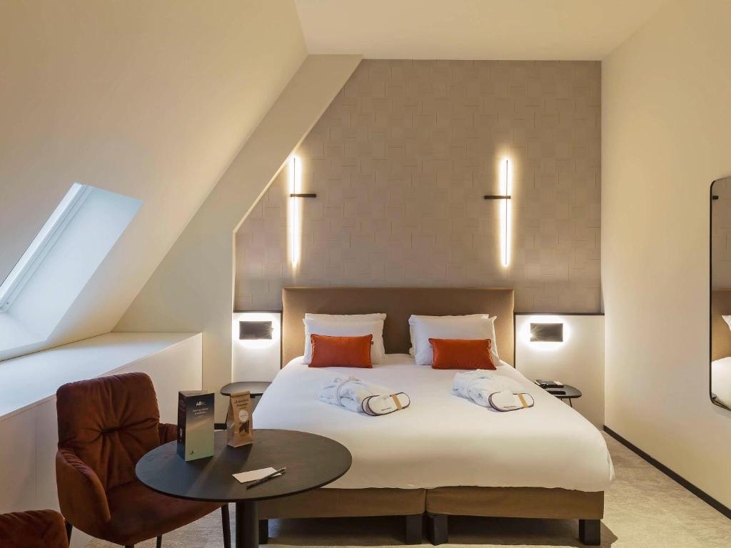 a bedroom with a large bed and a table at Mercure Namur Hotel in Namur