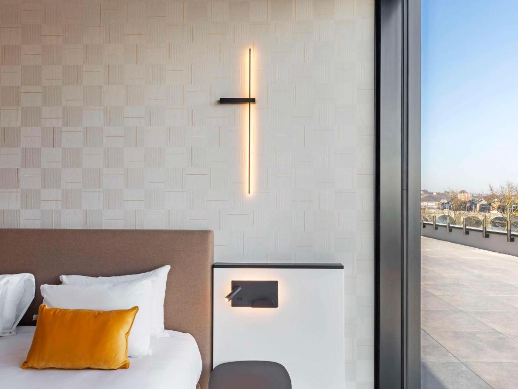 a bedroom with a bed with a light on the wall at Mercure Namur Hotel in Namur