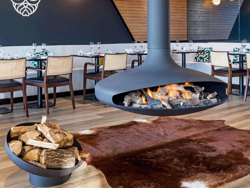 a fireplace in a restaurant with a table with chairs at Mercure Namur Hotel in Namur
