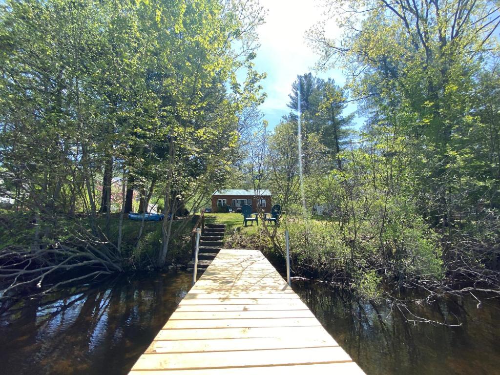 un puente de madera sobre un río con una casa en el fondo en Adirondack Waterfront Cabin Upper Hudson Tributary en Lake Luzerne