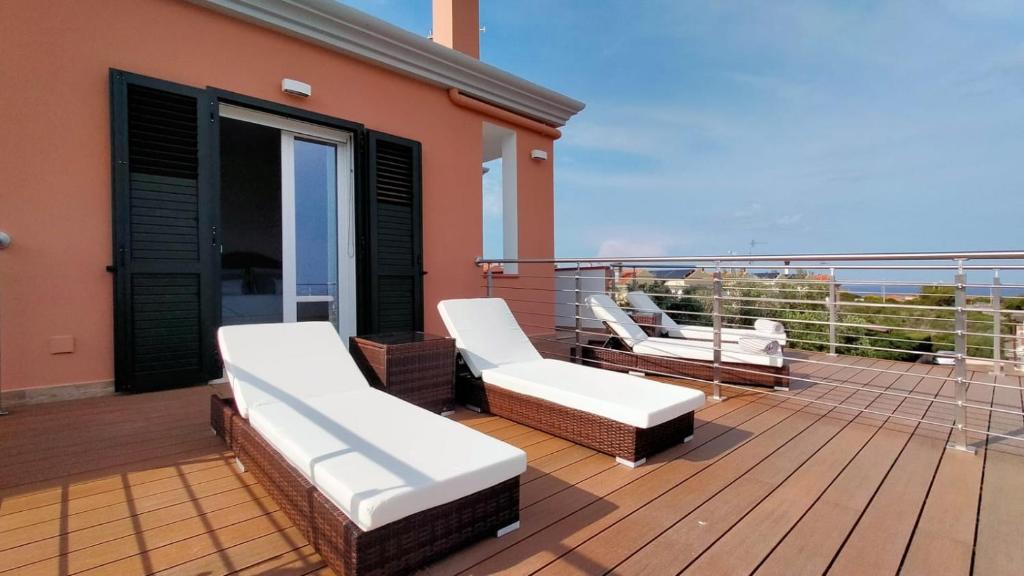 a balcony with white chairs and a view of the ocean at A.Mare in Stintino