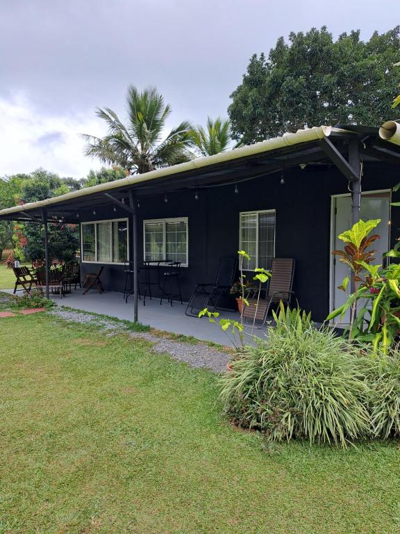 a black house with tables and chairs in a yard at Hospedaje Finca Agroturistica Doña Rufa in Río Sereno