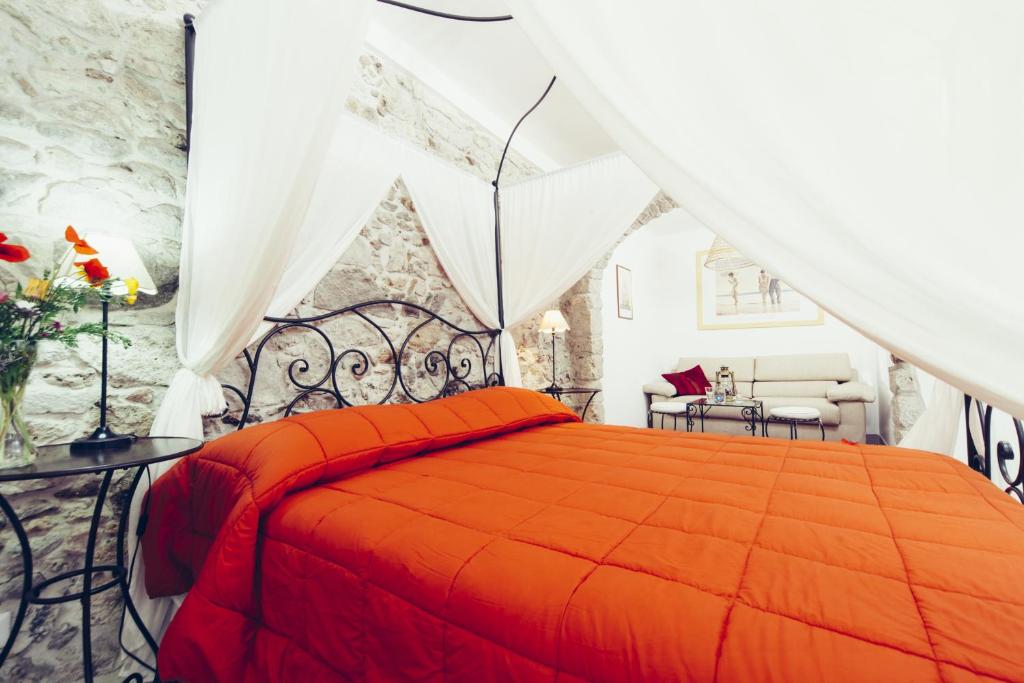um quarto com uma cama com uma colcha laranja em Blu Bosa em Bosa