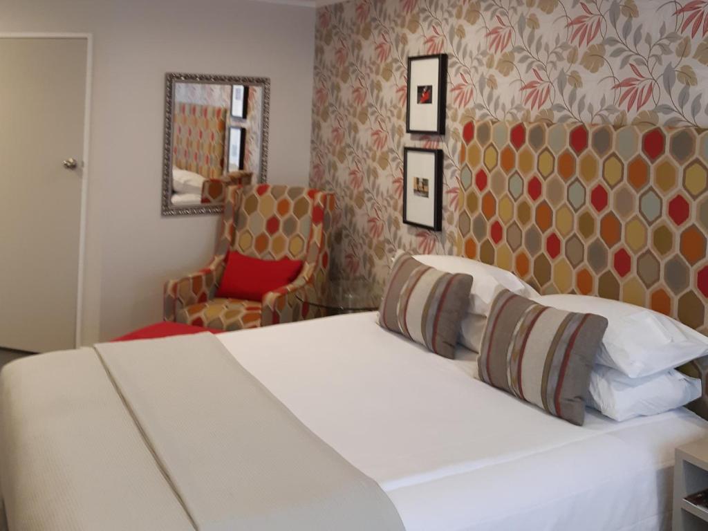 a bedroom with a white bed and a chair at ASURE Destiny on Fitzherbert Motel in Palmerston North