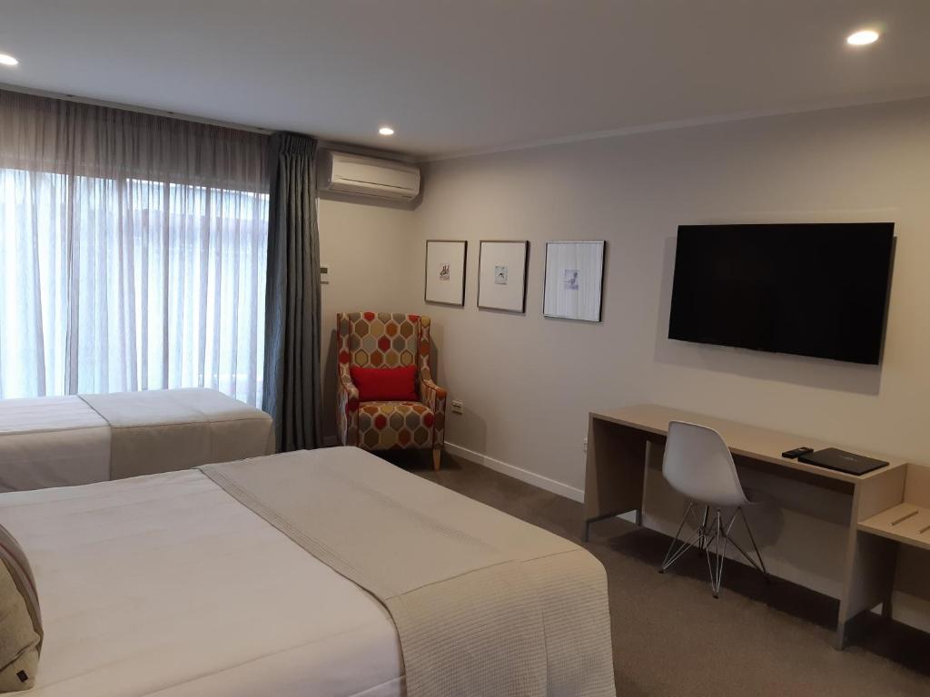 a hotel room with two beds and a desk and a television at ASURE Destiny on Fitzherbert Motel in Palmerston North