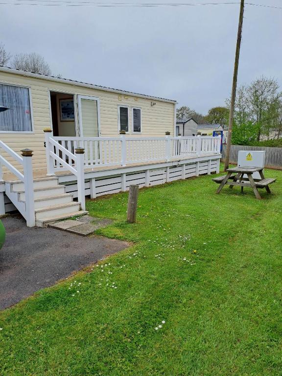 a house with a white porch and a picnic table at Sunblast- Dawlish Warren in Cockwood