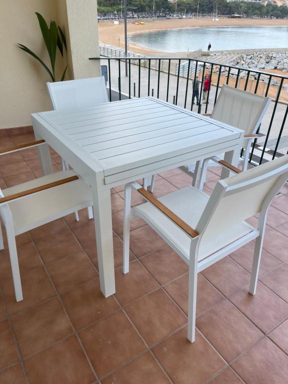 a white table and chairs with a view of the beach at Aquamarine Sant Feliu en la playa con patio in Sant Feliu de Guixols