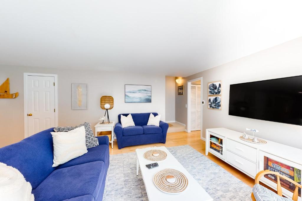 un salon avec un canapé bleu et une télévision dans l'établissement New Seabury Escape, à Mashpee