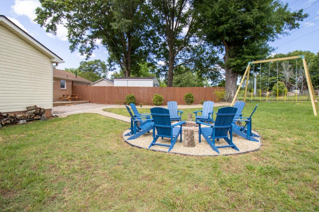 a group of blue chairs and a swing in a yard at Taylors Gem for Families - Charming Family Getaway in Taylors