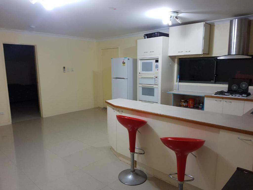 cocina con encimera y 2 taburetes rojos en Aspley property, en Brisbane