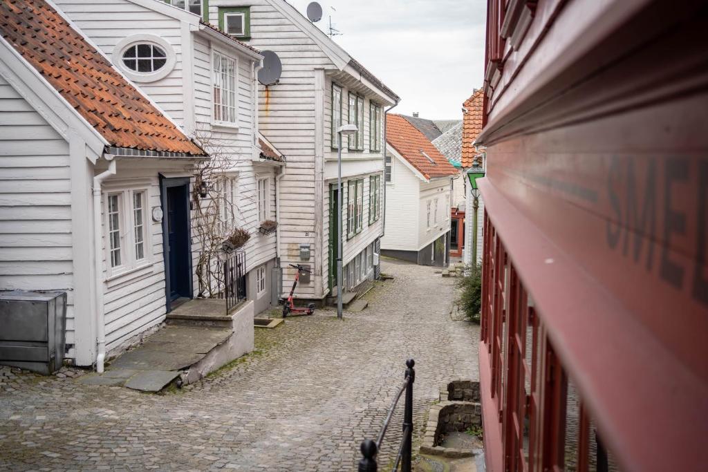 an alley with white houses and a cobblestone street at In Heart of Stavanger BnB with Billiard & Sauna in Stavanger