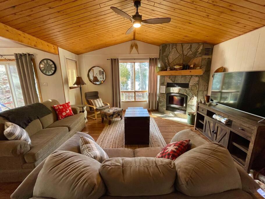 uma sala de estar com um sofá e uma televisão em Lakefront Chalet Style Cottage on SalmonTrout Lake em Maynooth