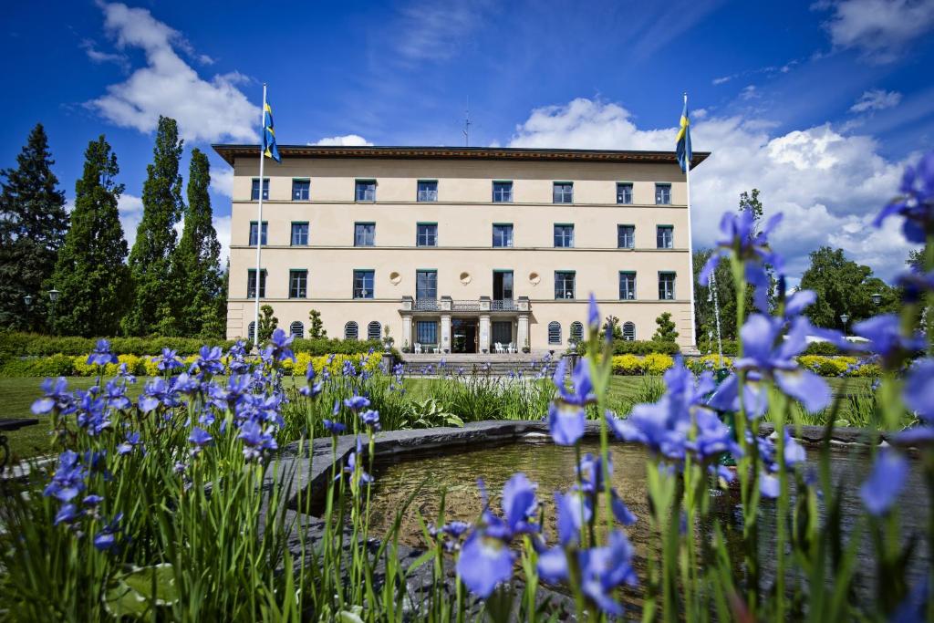 un edificio con flores azules delante de él en Bofors Hotel en Karlskoga