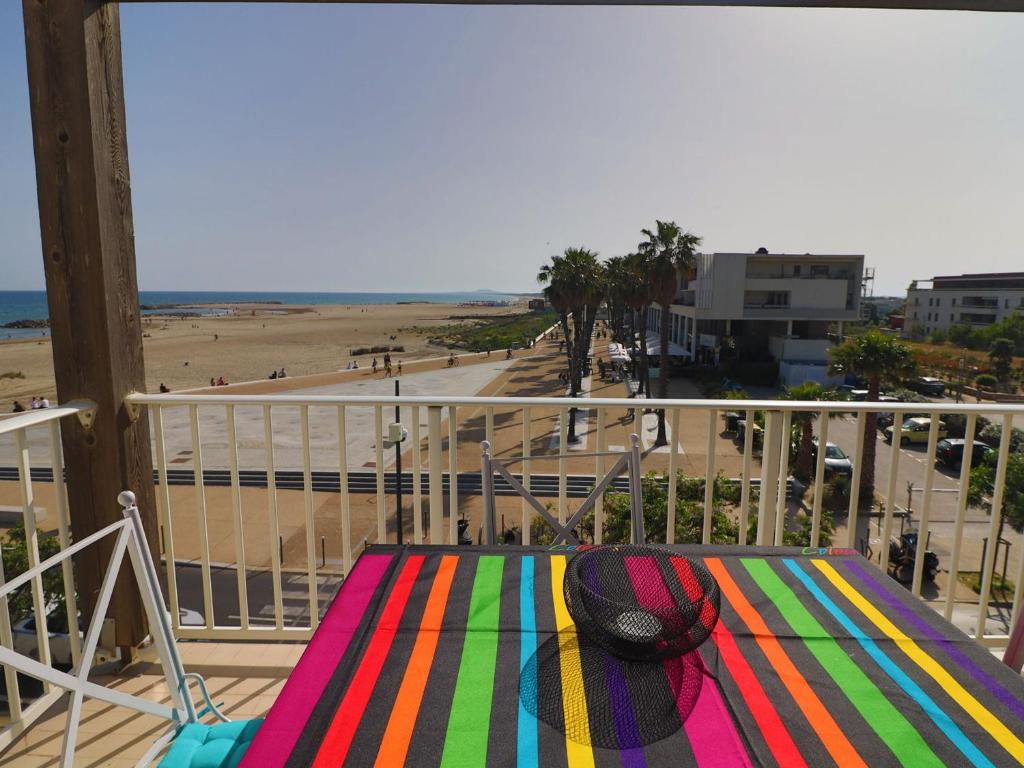 un balcon avec une table colorée et une vue sur une plage dans l'établissement Charmant 2 Pièces avec Terrasse et Parking à Sète - FR-1-472-191, à Sète