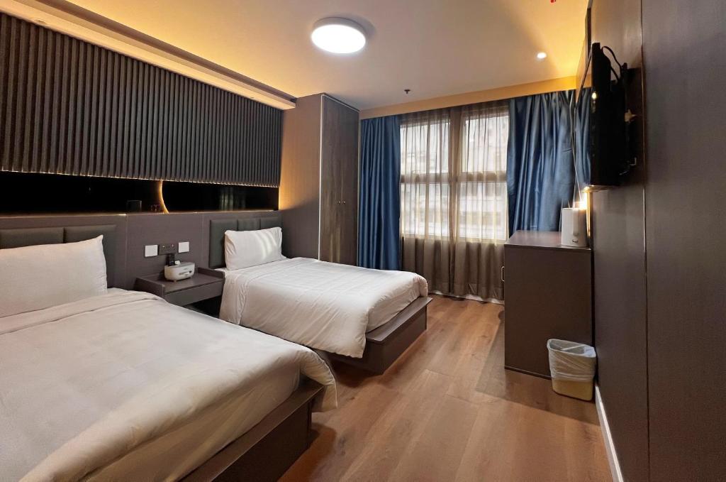 een hotelkamer met 2 bedden en een televisie bij Hennessy Hotel in Hong Kong