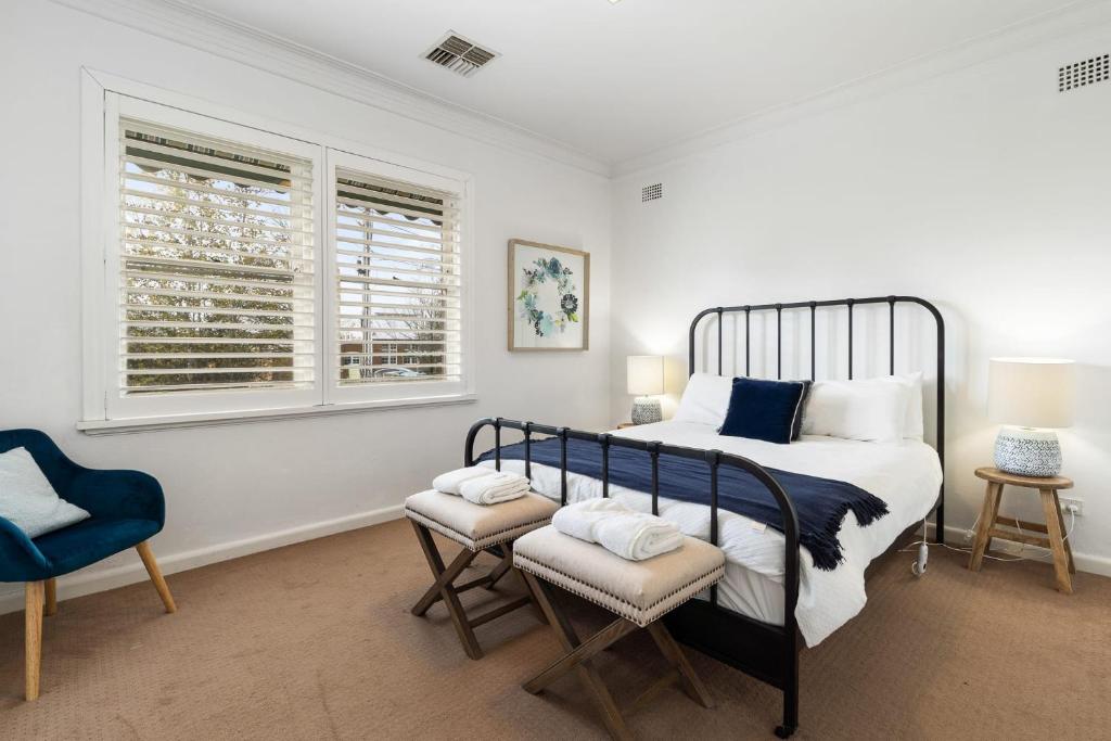 a bedroom with a bed and a chair and two windows at 105 Sale St STAY STYLISH IN THE HEART OF ORANGE in Orange