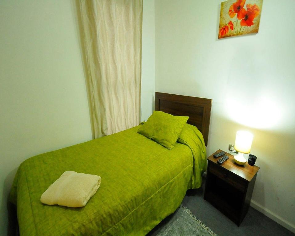 a small bedroom with a green bed and a night stand at Alojamientos San Sebastián Talca in Talca