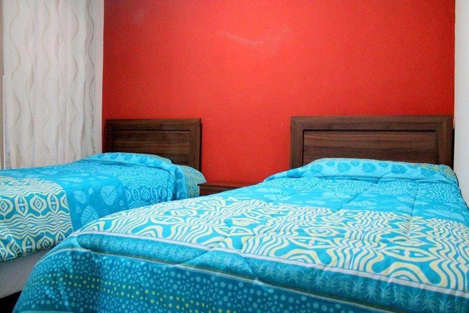 two beds in a room with red walls at Alojamientos San Sebastián Talca in Talca