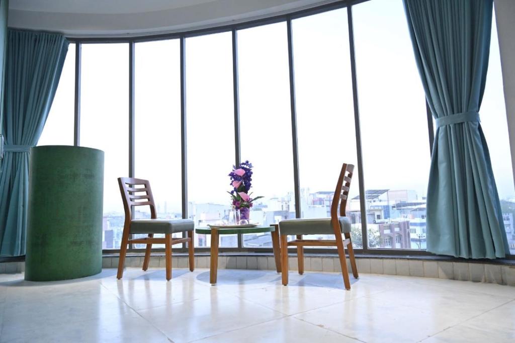 una mesa y 2 sillas en una habitación con ventanas en Hotel The Faam, en Rajkot