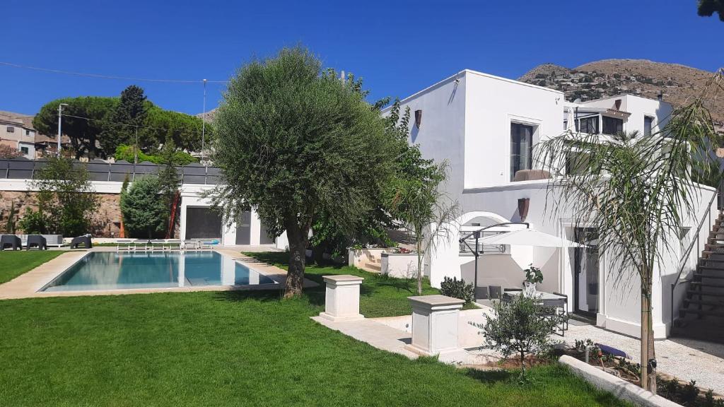 a white house with a swimming pool in a yard at FONDO MONDELLO in Mondello