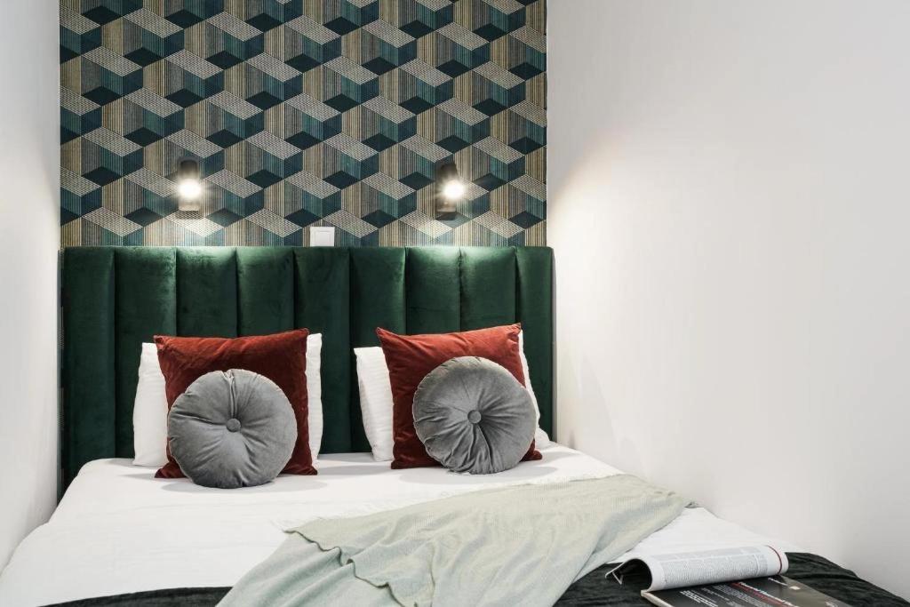 a bed with a green headboard and two pillows on it at Apartamenty na Jaworskiej Wrocław in Wrocław