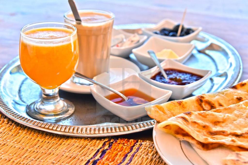 a table with a plate of food and a drink at Hotel-Restaurant Le Kaouki in Sidi Kaouki