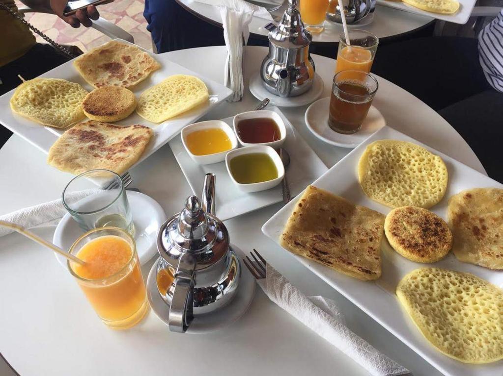 a white table topped with plates of food and drinks at Hotel-Restaurant Le Kaouki in Sidi Kaouki