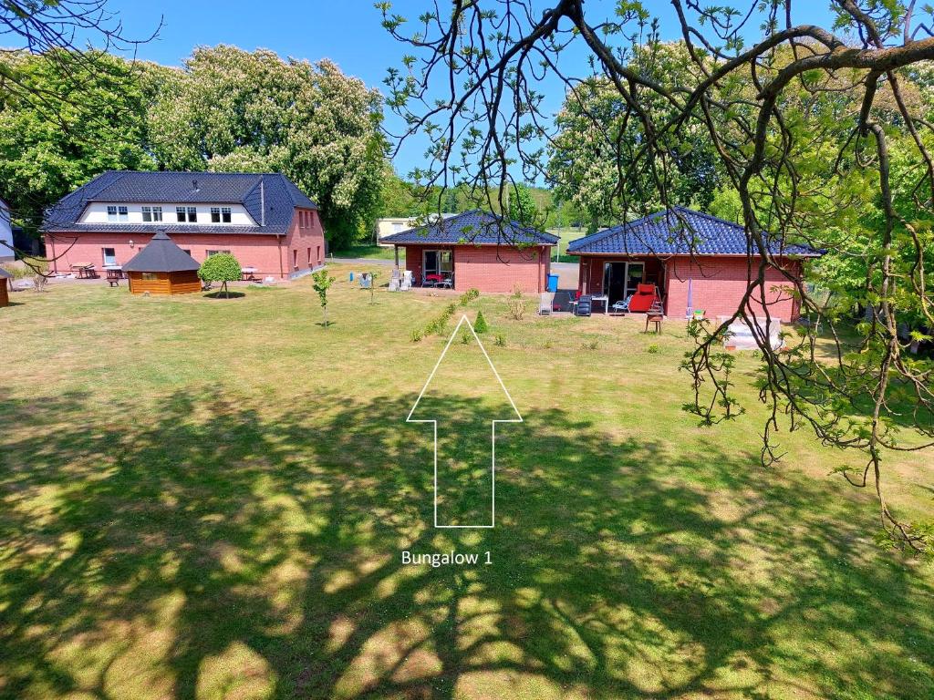 a yard with two houses and a field with trees at Rügen Schaprode Bungalow - barrierefrei - kleine Hunde auf Anfrage willkommen in Schaprode