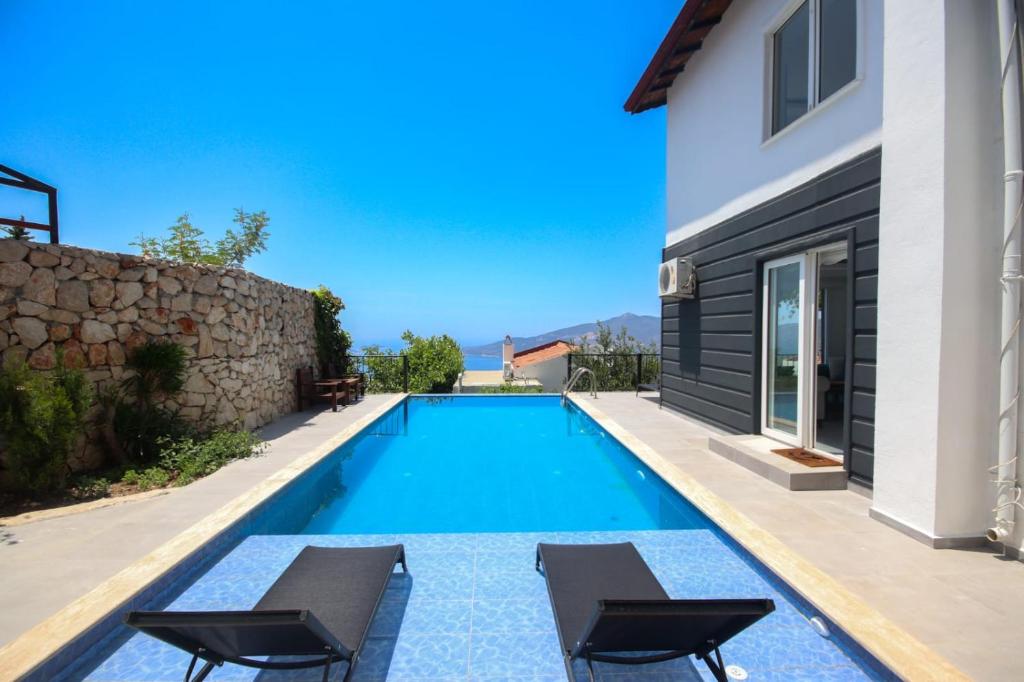 a swimming pool with two chairs and a house at Villa MK in Kalkan
