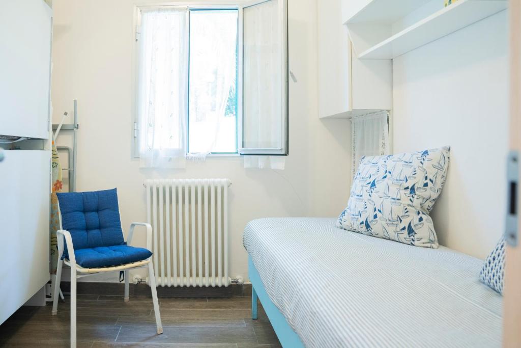 niewielka sypialnia z łóżkiem i niebieskim krzesłem w obiekcie 070 - Villa OLANDA con veranda VISTA MARE a 5 minuti SPIAGGIA con PISCINA CONDOMINIALE w mieście Sestri Levante