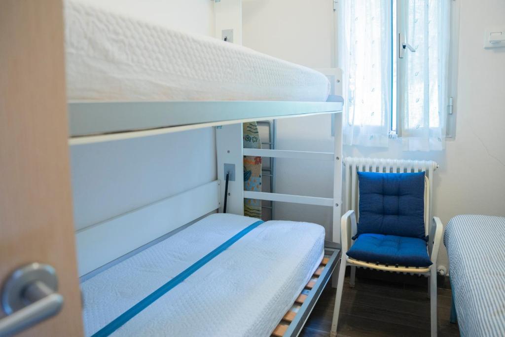 sypialnia z łóżkiem piętrowym i niebieskim krzesłem w obiekcie 070 - Villa OLANDA con veranda VISTA MARE a 5 minuti SPIAGGIA con PISCINA CONDOMINIALE w mieście Sestri Levante