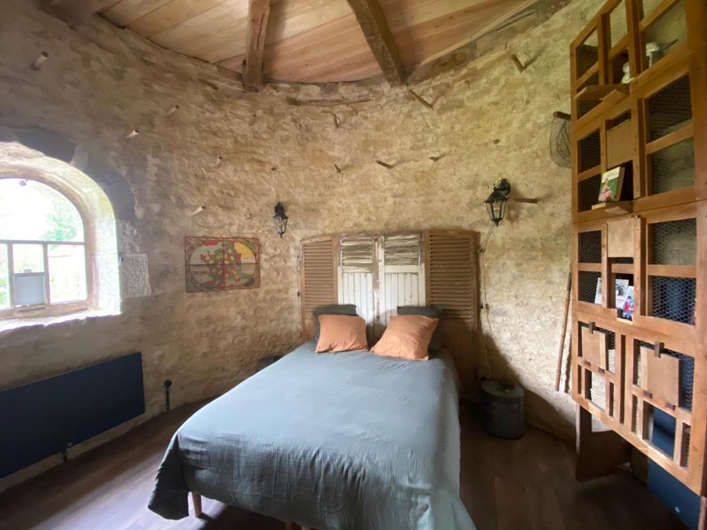 a bedroom with a bed in a stone wall at Le Colombier de Malpas in Quingey