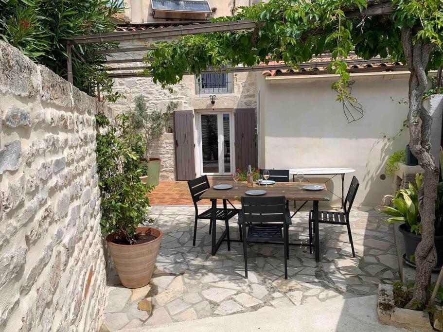 un patio con mesa y sillas en un edificio en La Jas, demeure climatisée au charme gardois., en Nages-et-Solorgues