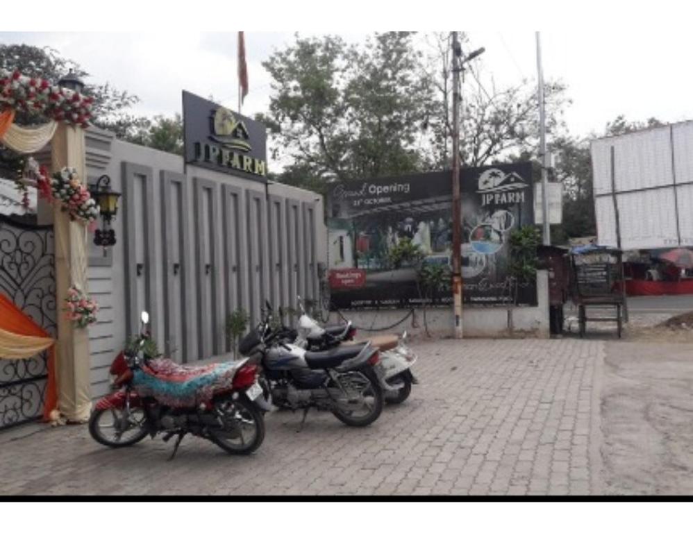 two motorcycles parked on a brick sidewalk next to a building at J P Farm, Jhansi in Jhānsi