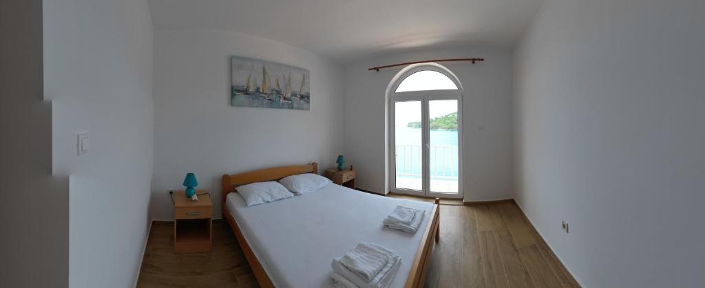 une chambre avec un grand lit et une fenêtre dans l'établissement Mljet Sunset Apartments, à Pomena