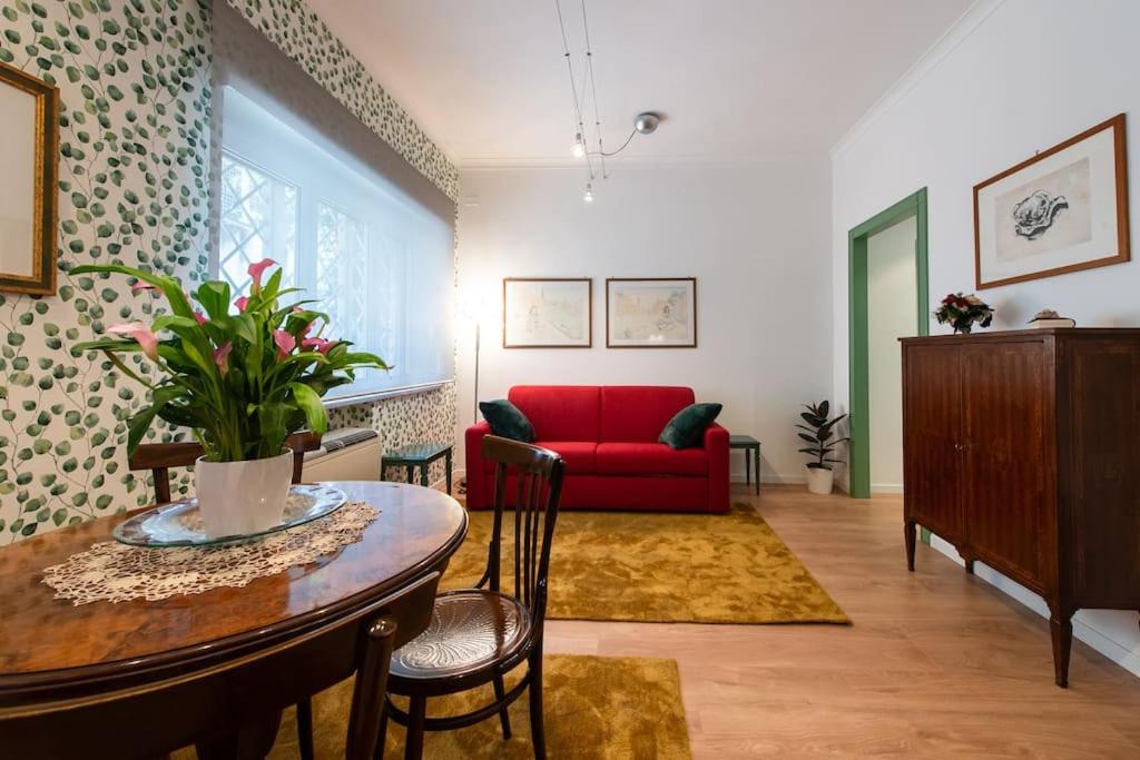 a living room with a red couch and a table at Casa Bouganville - St. Peter Romantic Apartment in Rome