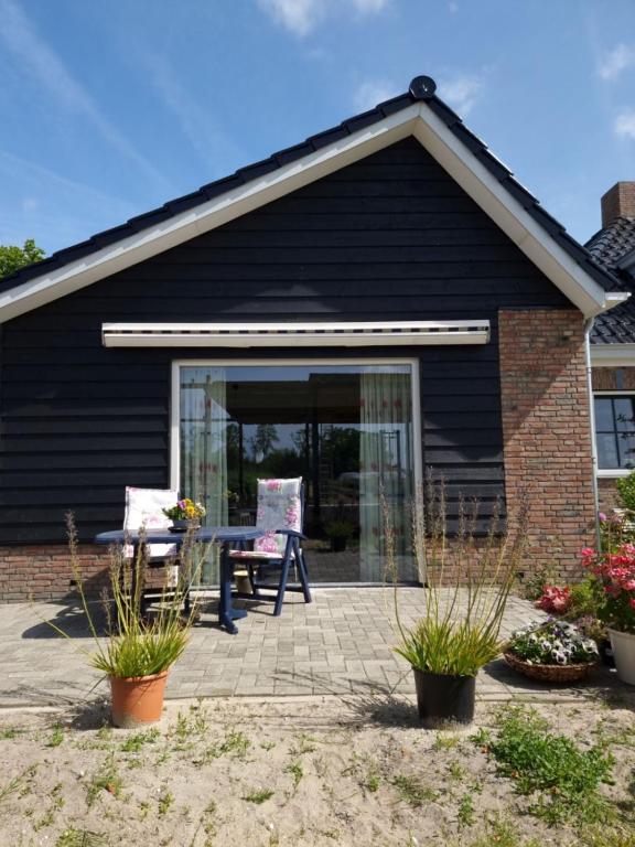 una casa nera con patio e tavolo di De Bloemenkwekerij a Egmond-Binnen