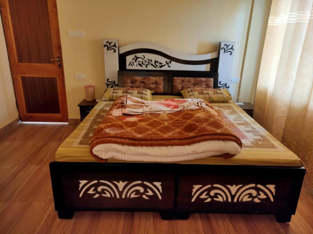 ein großes Bett in einem Schlafzimmer mit Holzboden in der Unterkunft Conifers Homestay in Shimla