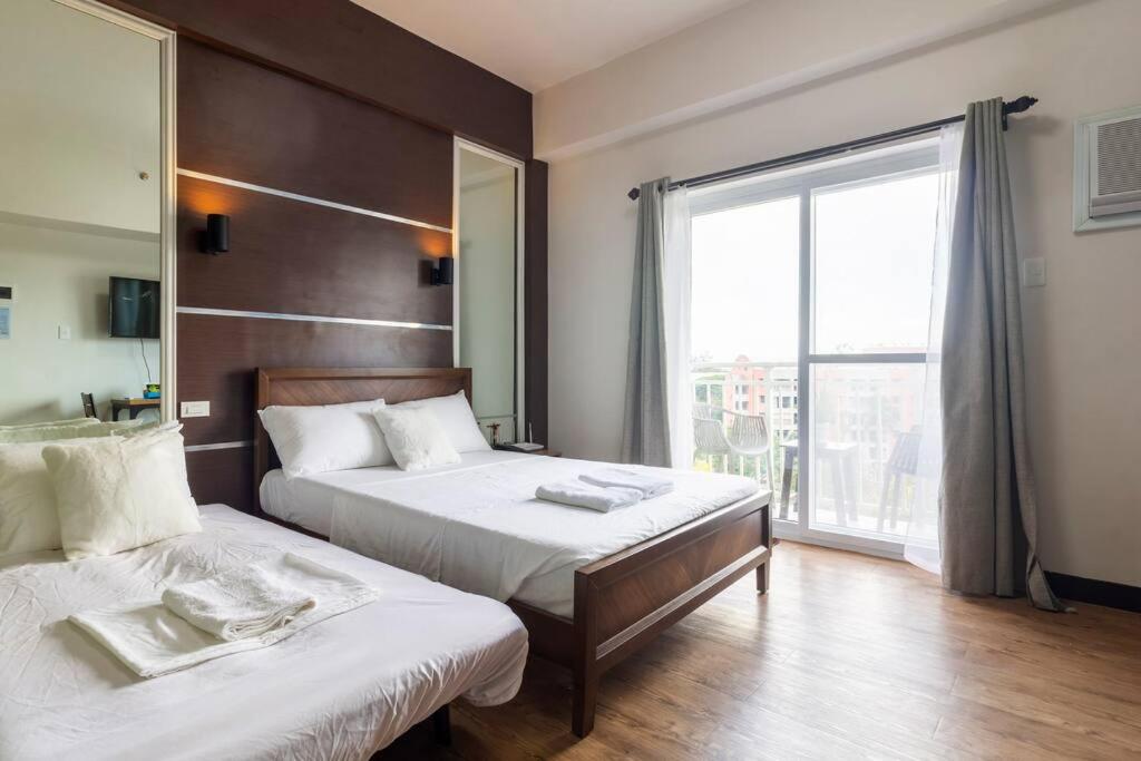 1 dormitorio con 2 camas y ventana grande en Antonio's Place, 3 mins to Mactan Airport, Fast Internet with Netflix, en Mactan