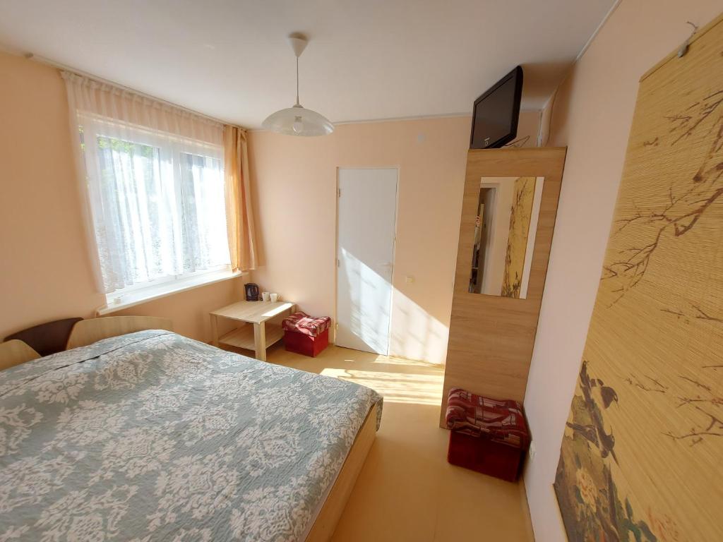 a bedroom with a bed and a tv on a wall at Neringos 8 in Palanga