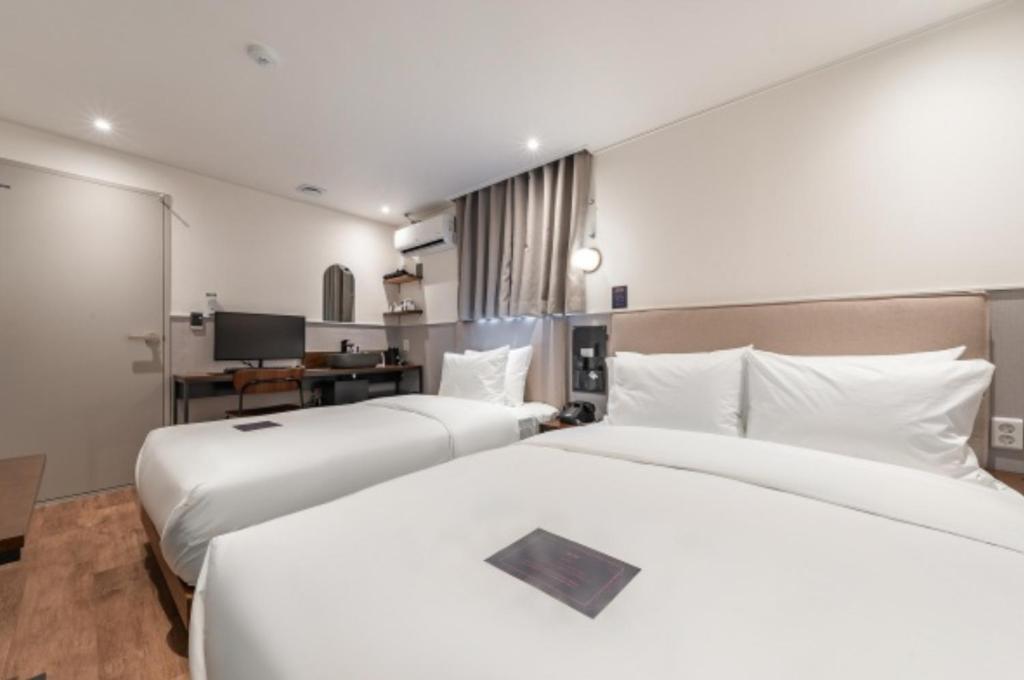 a hotel room with two beds and a desk at Just Stay Hotel in Seoul