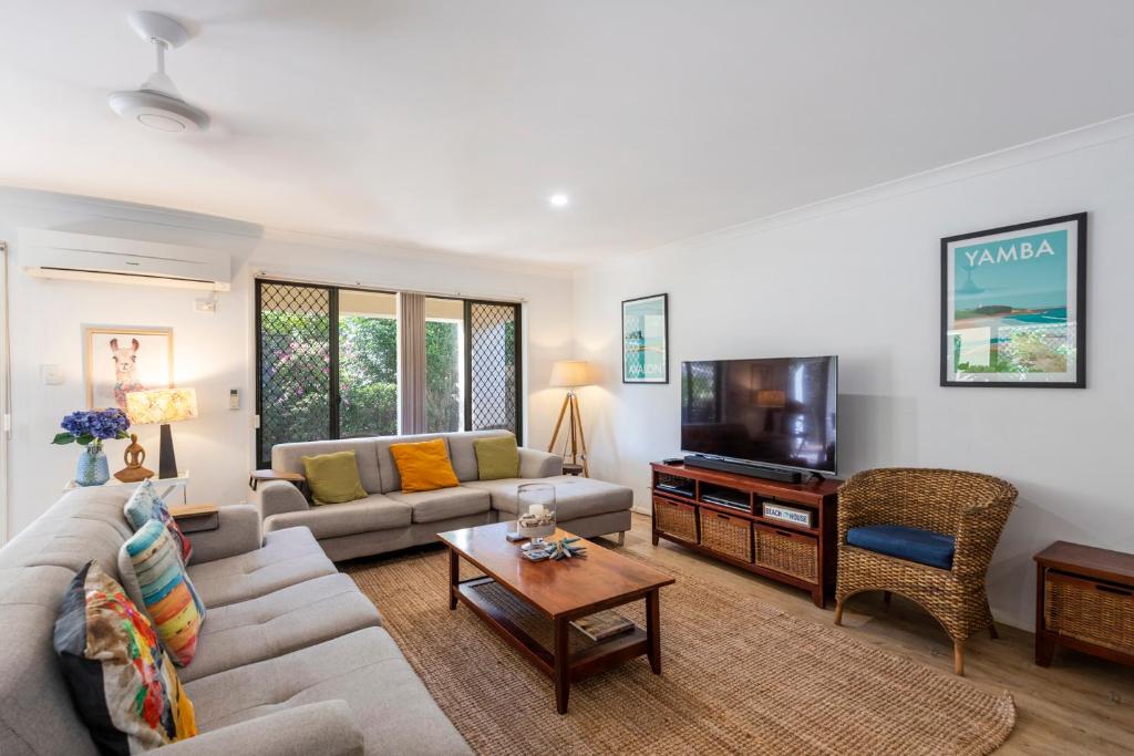 a living room with a couch and a tv at 32 Beachside - LJHooker Yamba in Yamba