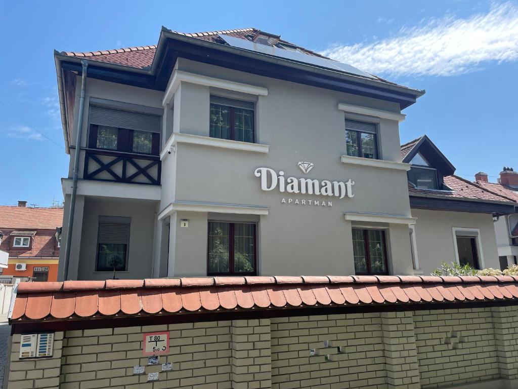 a white building with a sign on top of a brick wall at Diamant Apartmanház in Eger