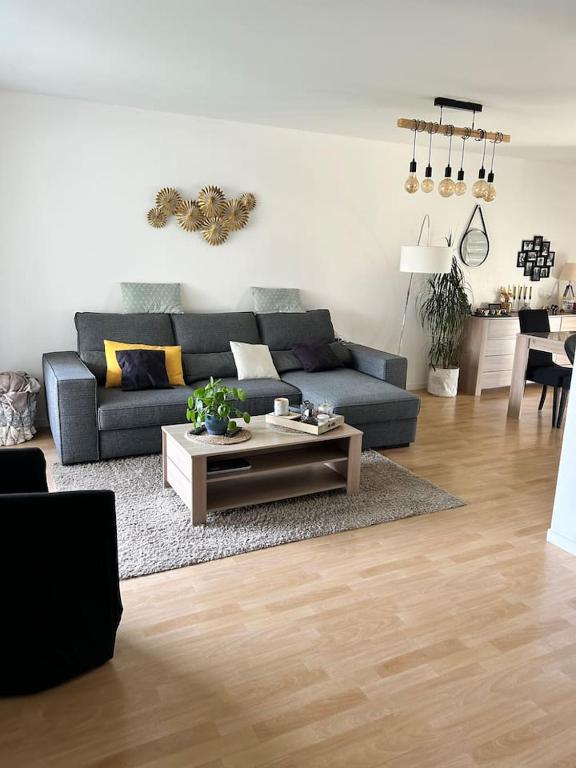 un salon avec un canapé bleu et une table basse dans l'établissement Appartement une chambre proche centre ville et transports, au Mans