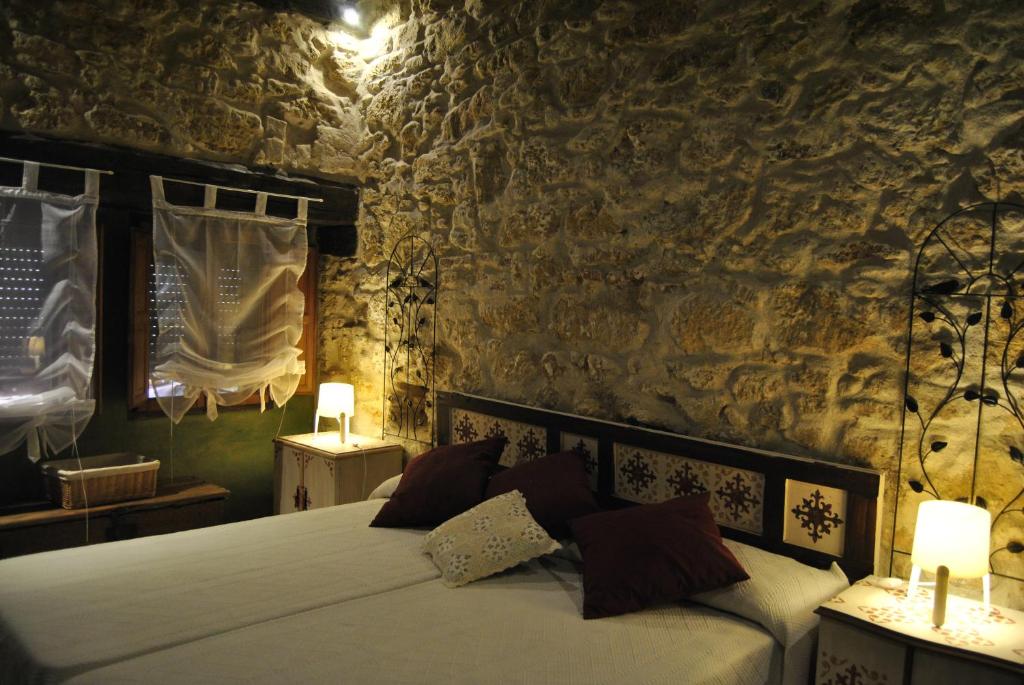 1 dormitorio con 1 cama en una pared de piedra en Casa Rural Los Secretos, en Carbonero de Ahusín