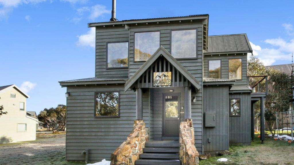 una casa gris con una escalera delante de ella en Altitude en Dinner Plain