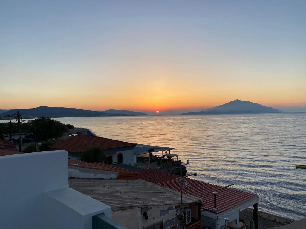 un coucher de soleil sur l'eau avec des montagnes en arrière-plan dans l'établissement Passatempo Apartment Ireon, à Samos