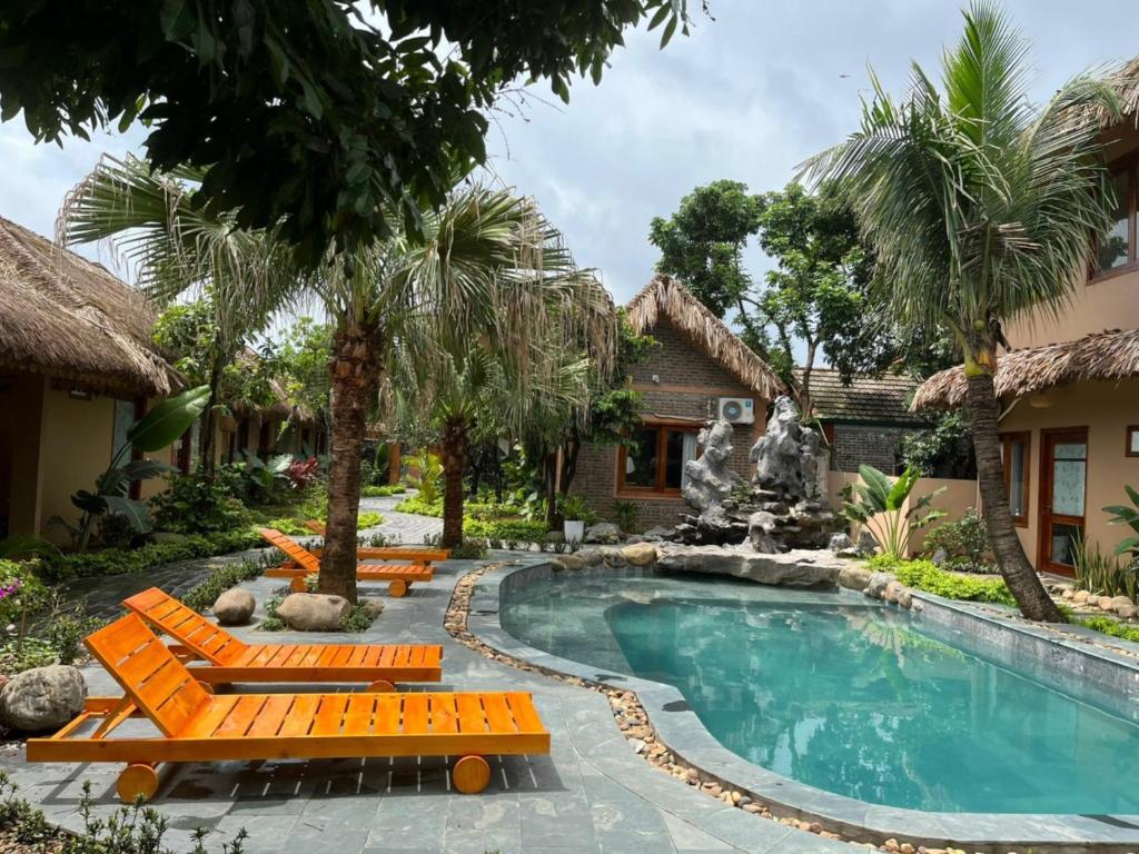 a resort pool with lounge chairs and a fountain at Lemon Tree Homestay Tam Coc in Ninh Binh