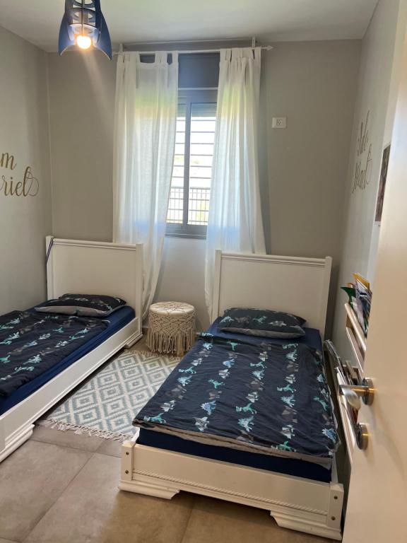 2 łóżka pojedyncze w pokoju z oknem w obiekcie דירת גן מהממת בבית שמש w mieście Bet Szemesz