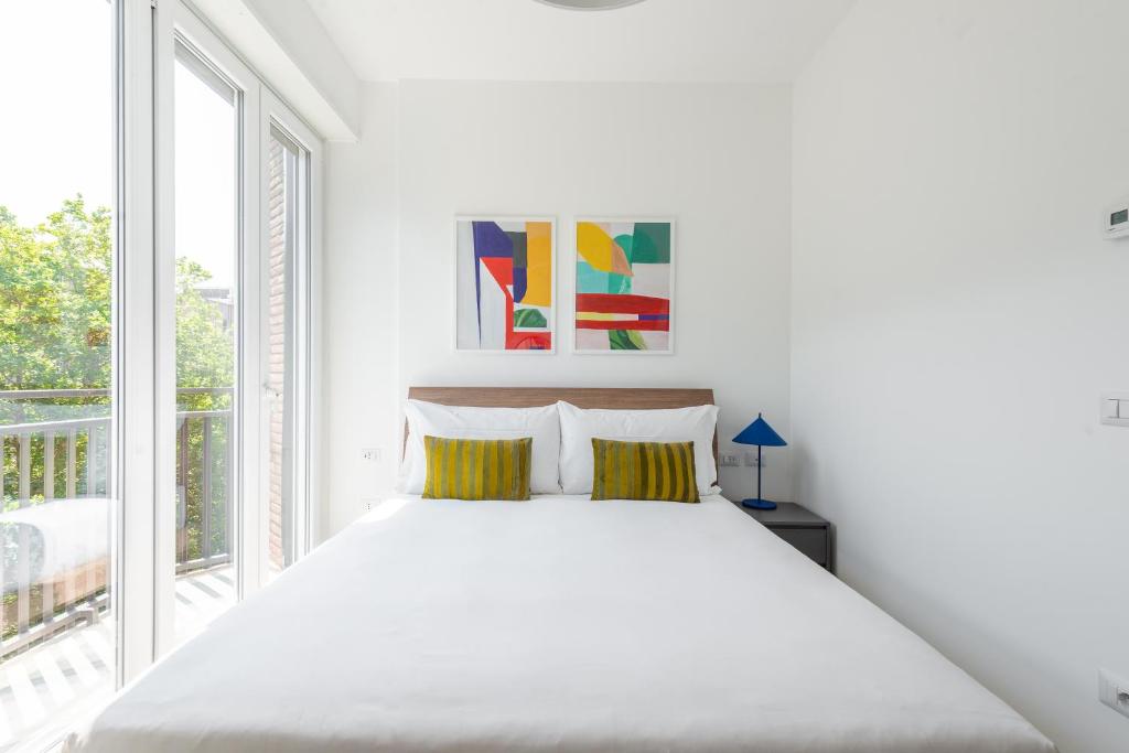 a white bedroom with a bed and a large window at numa I Verso Apartments in Rome